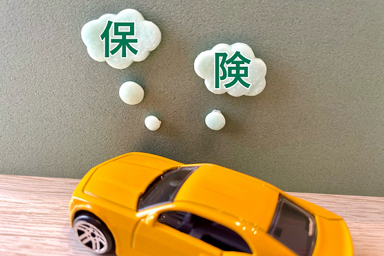 「保険」という文字の吹き出しと黄色い車の模型の画像